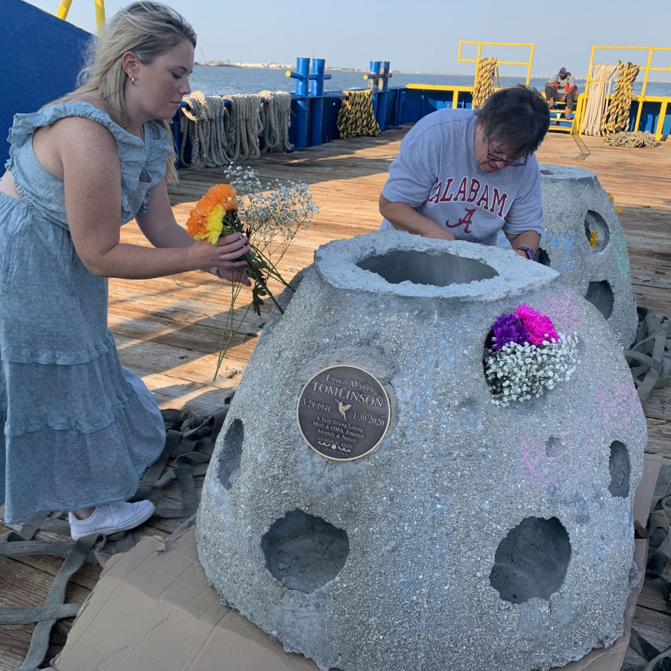 Family placing flowers on reef ball on barge