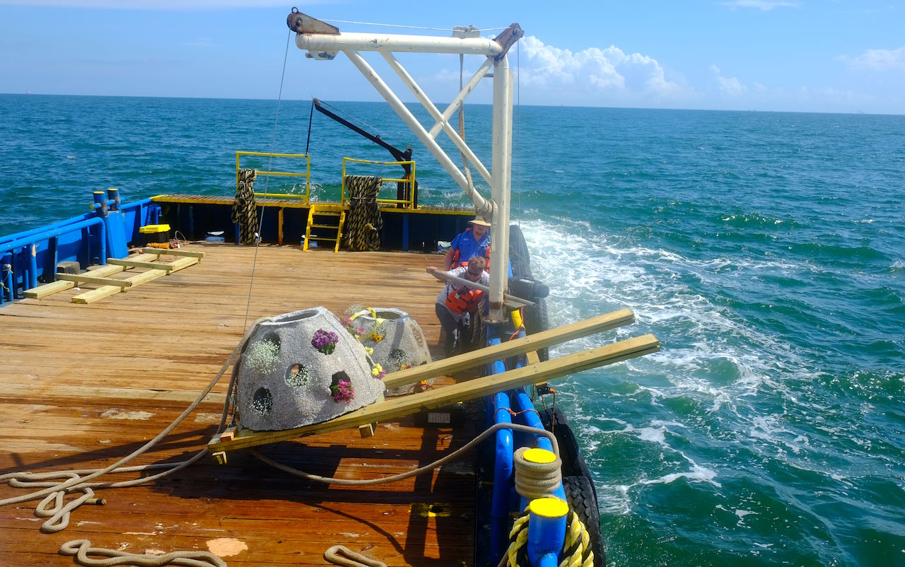 reef balls on a boat about to be lowered into the ocean by crew